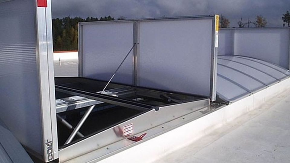 Rooftop with an open smoke and heat exhaust ventilation system (shevs), set against a cloudy sky.