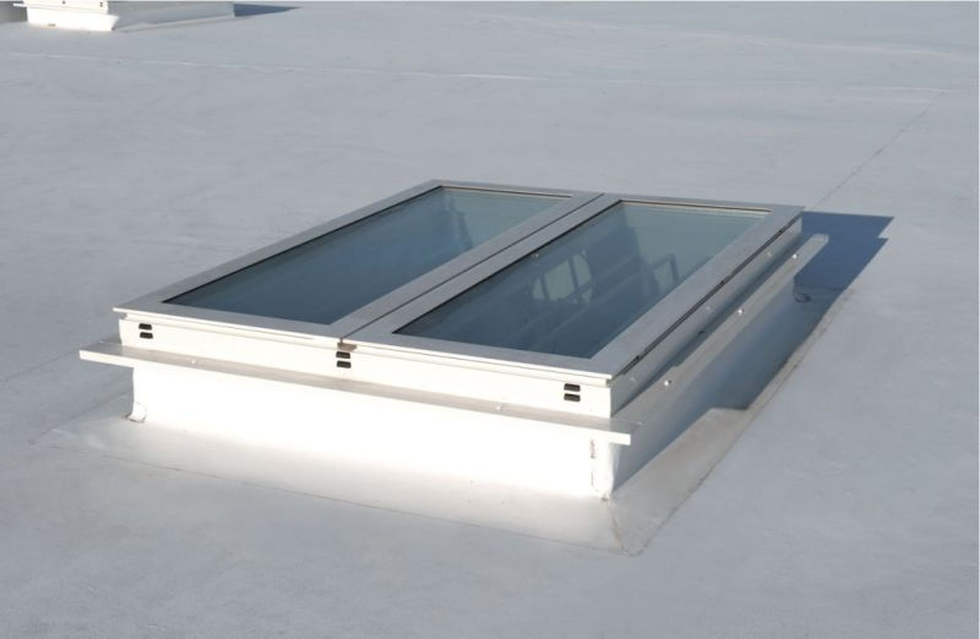 A flat white rooftop with a rectangular Firelight Duo featuring two glass panels framed in white.