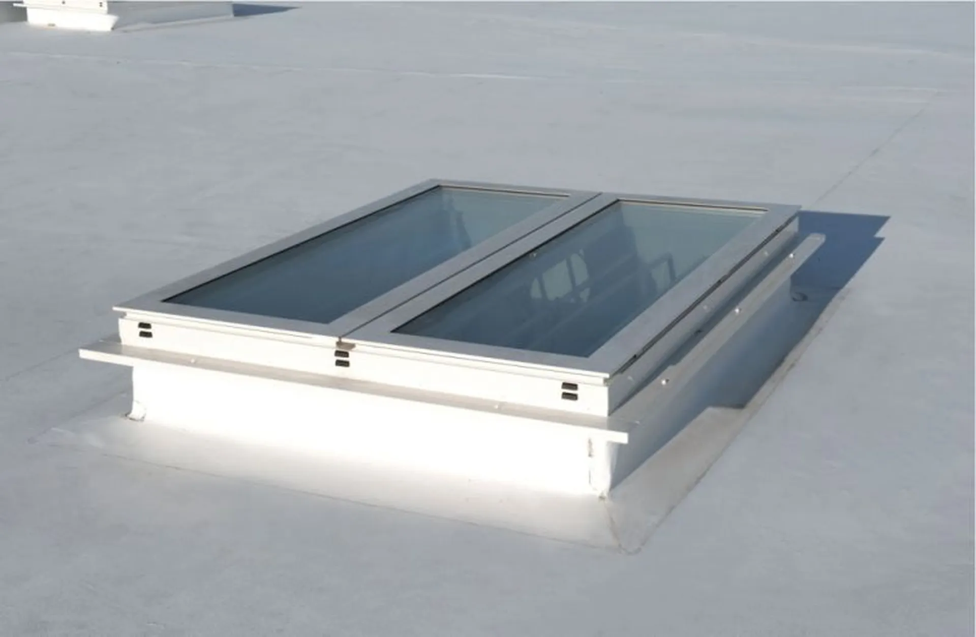 A flat white rooftop with a rectangular Firelight Duo featuring two glass panels framed in white.