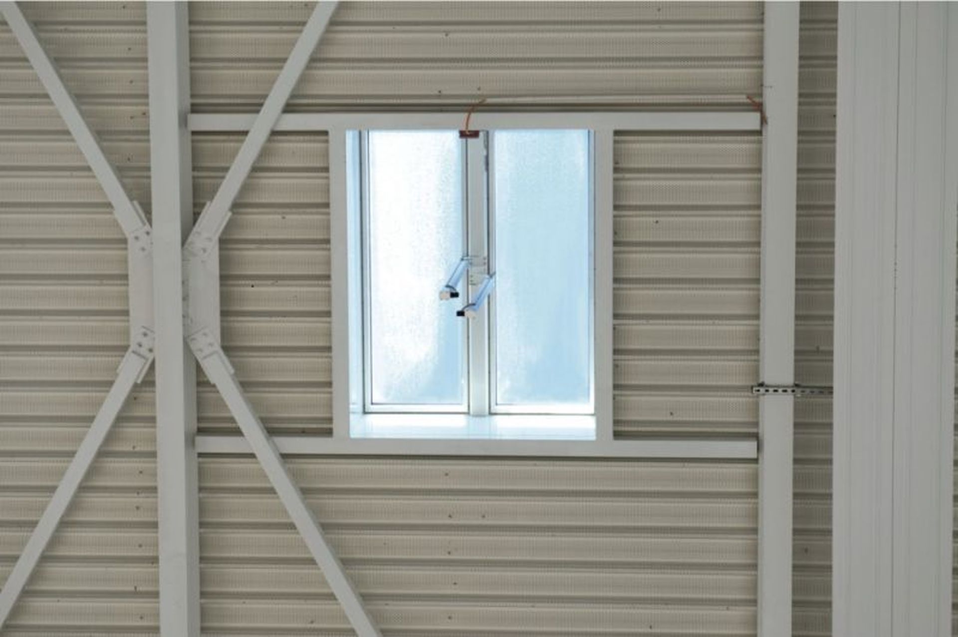 A Firelight Duo with frosted glass framed by structural beams on a ribbed metal wall.