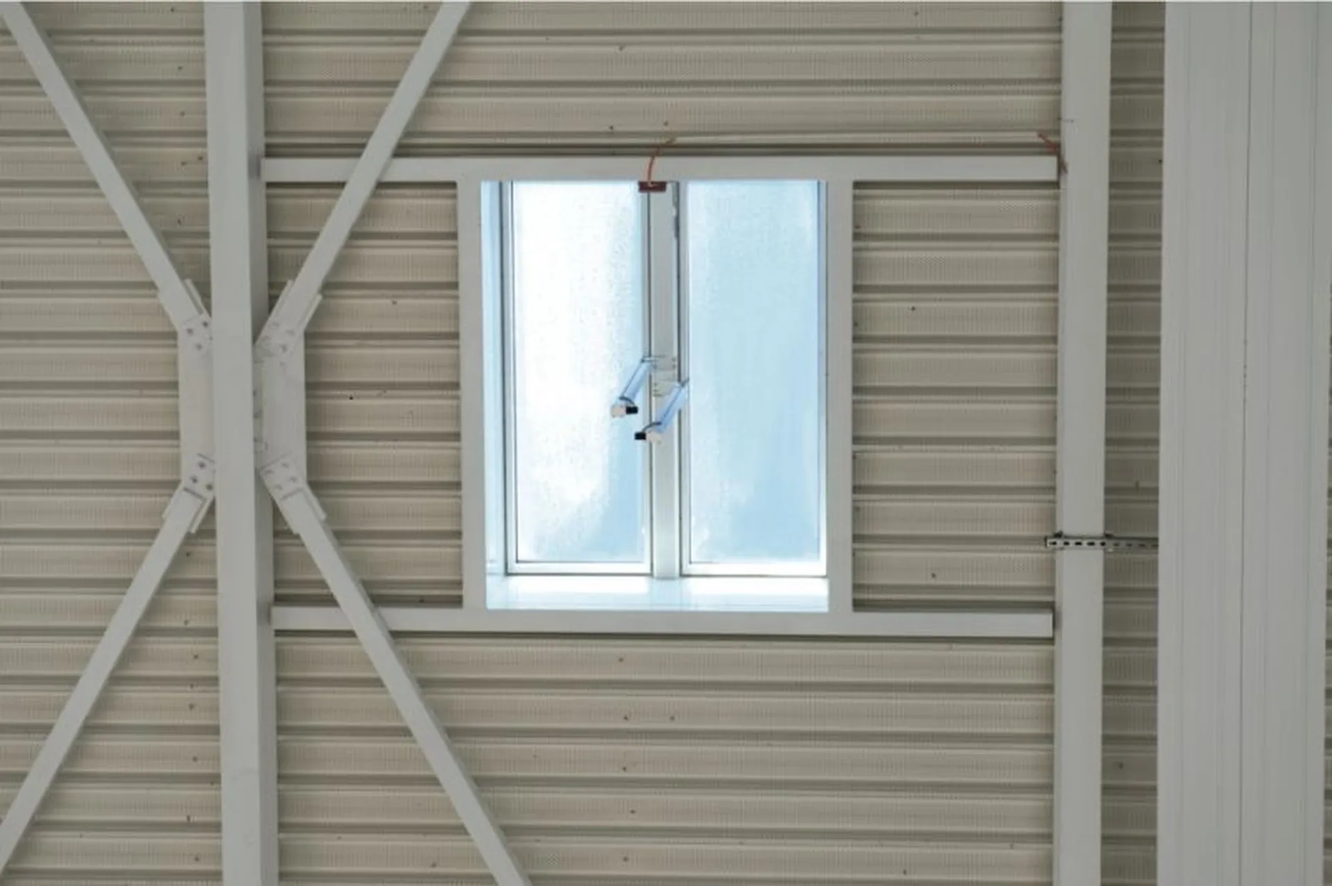 A Firelight Duo with frosted glass framed by structural beams on a ribbed metal wall.