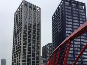 Tall modern London skyscrapers against a grey sky, with a red bridge structure in the foreground.