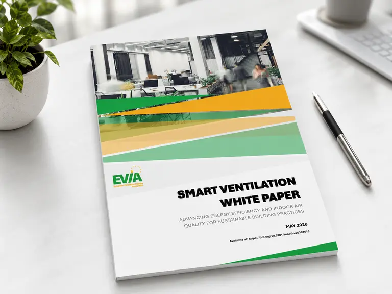 Mockup des EVIA Whitepapers „Smart Ventilation“ auf einem Schreibtisch in moderner Büroumgebung mit Pflanze und Stift.