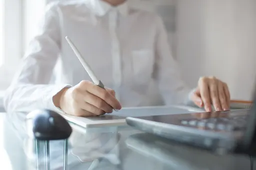 Business Frau am Schreibtisch vor dem Laptop und iPad