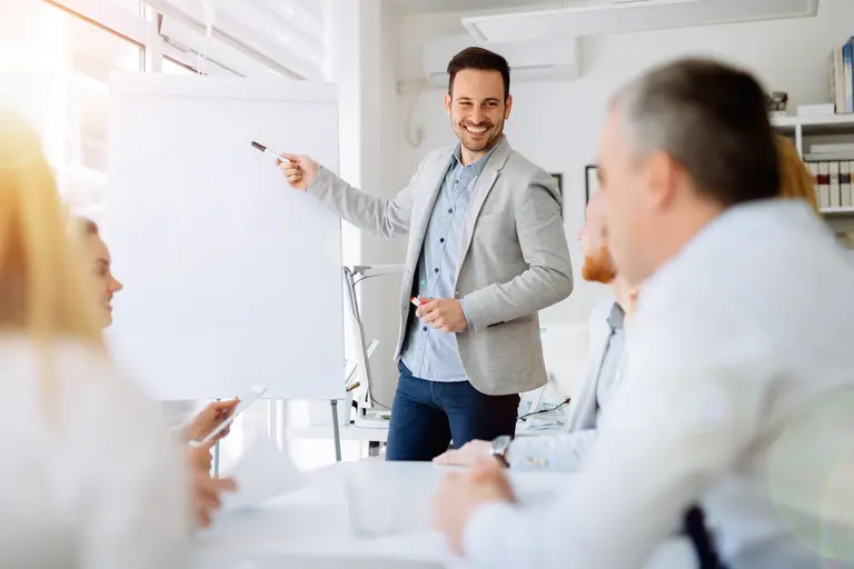 Mann moderiert eine Präsentation zur professionellen Planungsunterstützung von Schullüftungsprojekten in einem Büro.