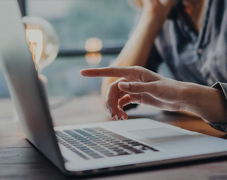 Hand einer Frau zeigt mit dem Zeigefinge auf einen Laptop