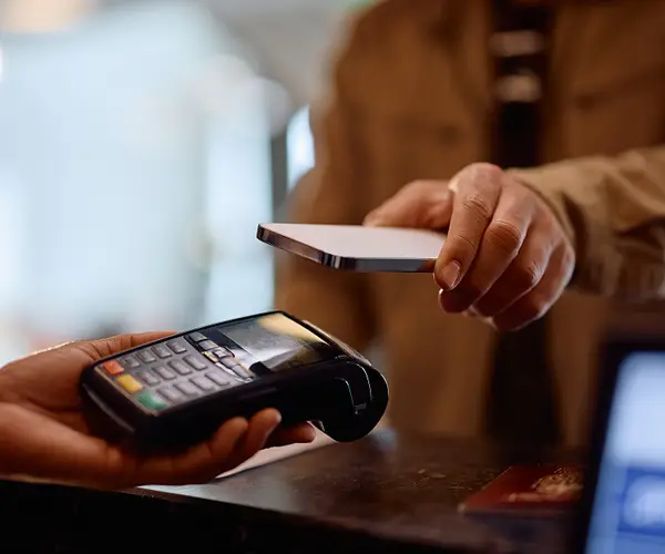 Cliente pagando uma compra por aproximação com o celular em uma maquininha de cartão.