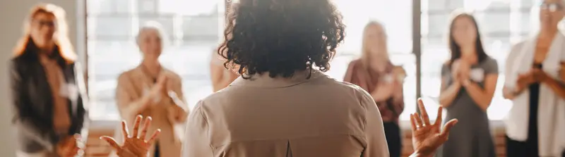 Grupo de profissionais reunidos em círculo durante uma dinâmica colaborativa, representando trabalho em equipe e propósito coletivo