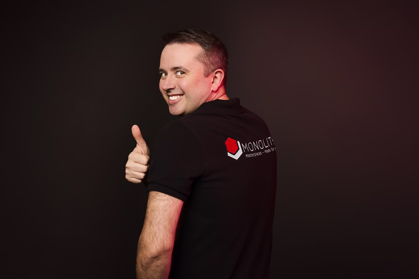 Alexander Herliz mit zeigt den Daumen und MONOLITH auf dem Rücken