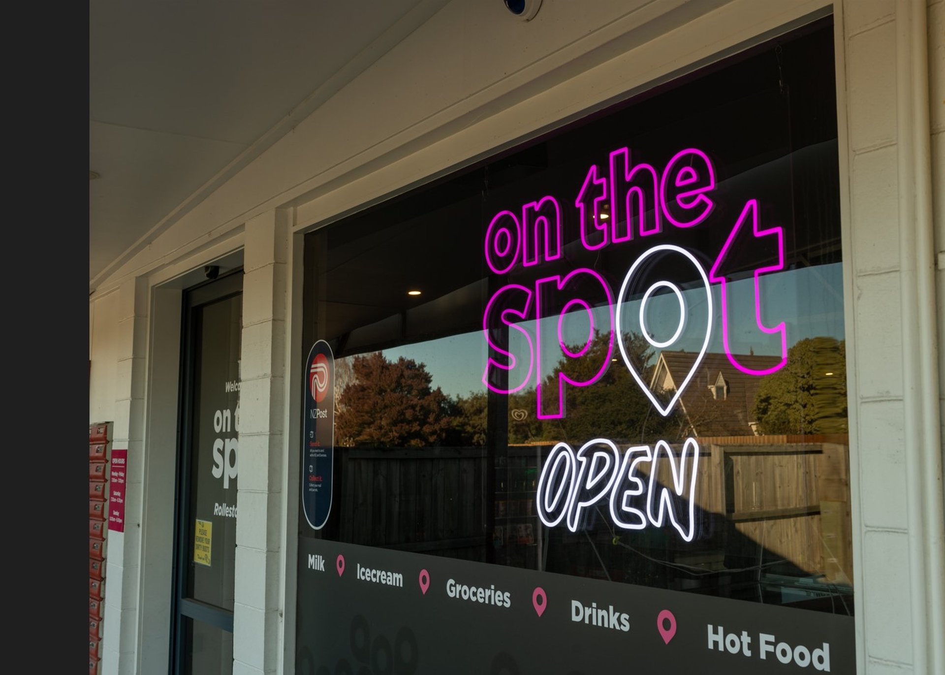 Storefront with a neon sign reading "on the Spot OPEN"