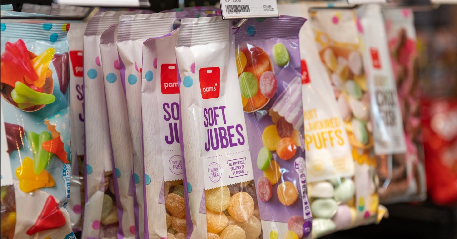 assorted candies hanging on a display rack, including soft jubes and fruit-flavored sweets.