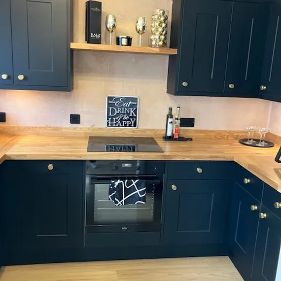 Modern kitchen with dark cabinets, wooden countertops, electric stove, and decor including wine bottles, glasses, and a chalkboard sign.