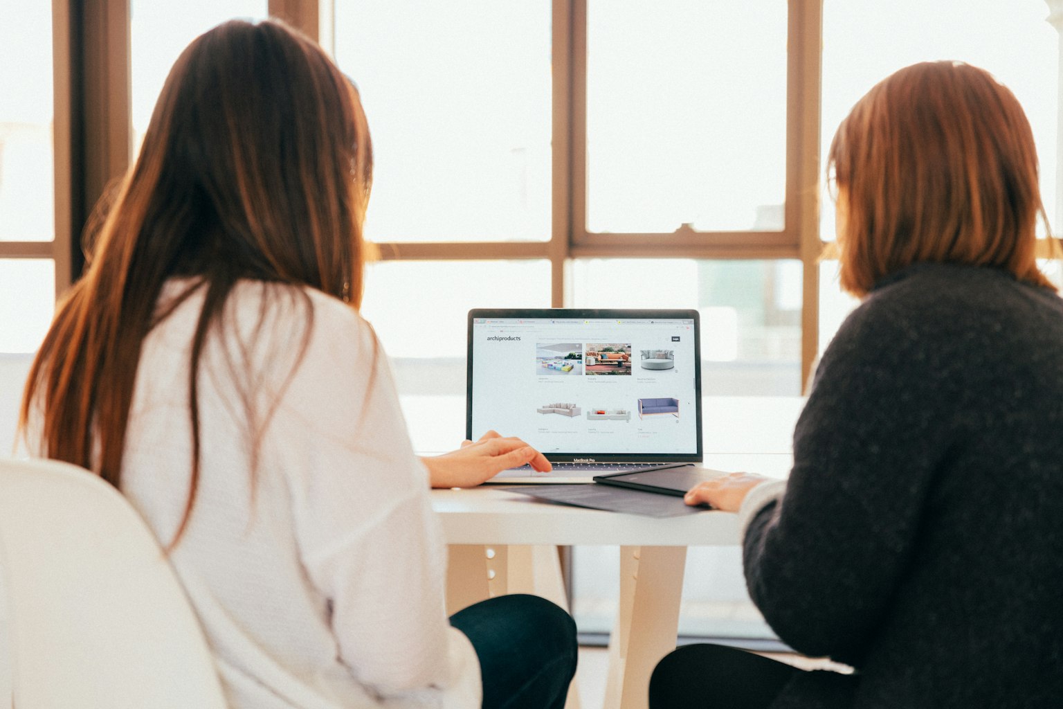 Två personer som granskar en webbsida på en laptop