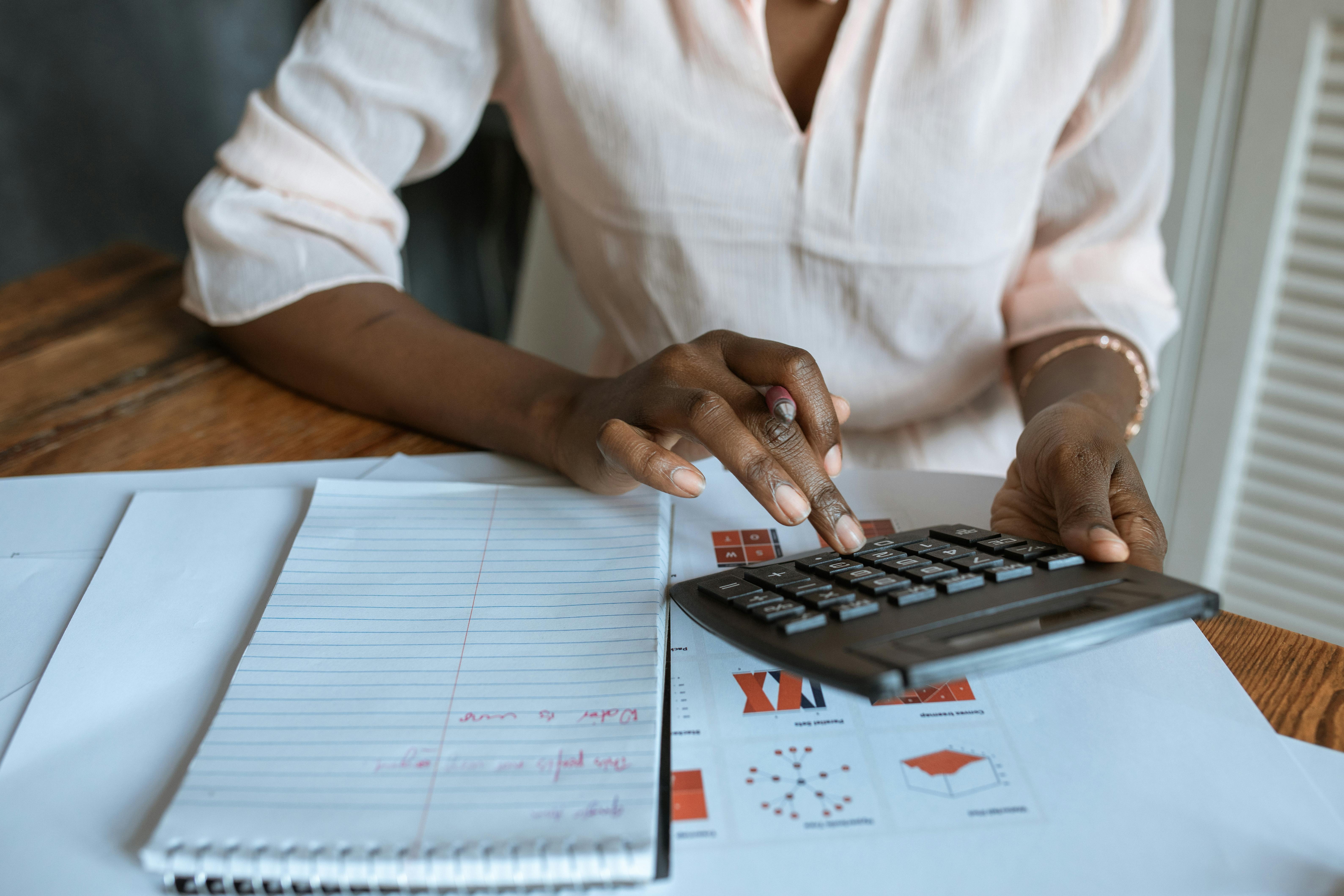Person berechnet Fördermittel und Projektkosten mit Taschenrechner – Finanzplanung für Startup-Förderantrag