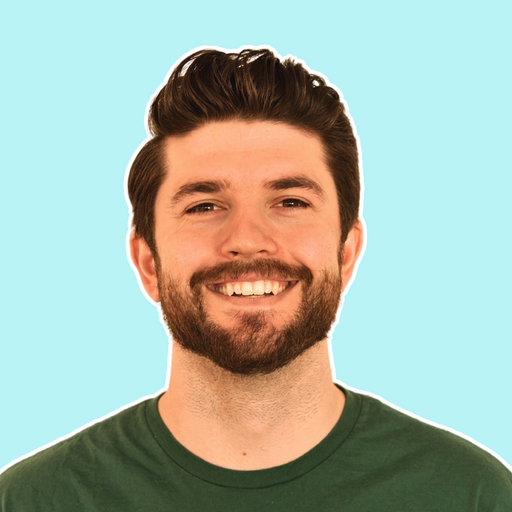 Smiling young man with dark hair and beard wearing a green t-shirt against a light blue background