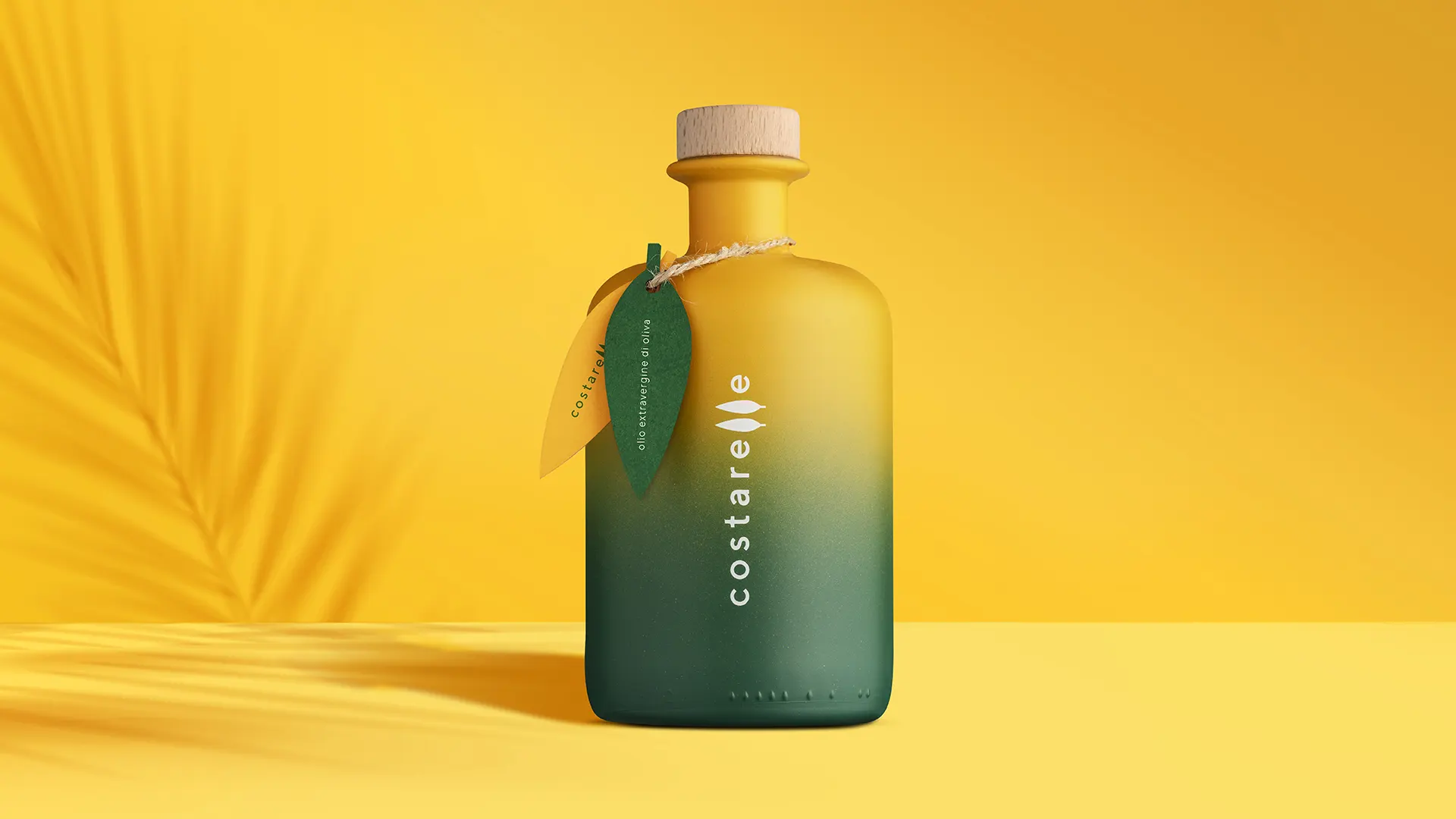 Bottiglia di olio extravergine Costarelle con packaging sfumato dal giallo al verde scuro, tappo in legno naturale e pendaglio a forma di foglia, su sfondo giallo oro