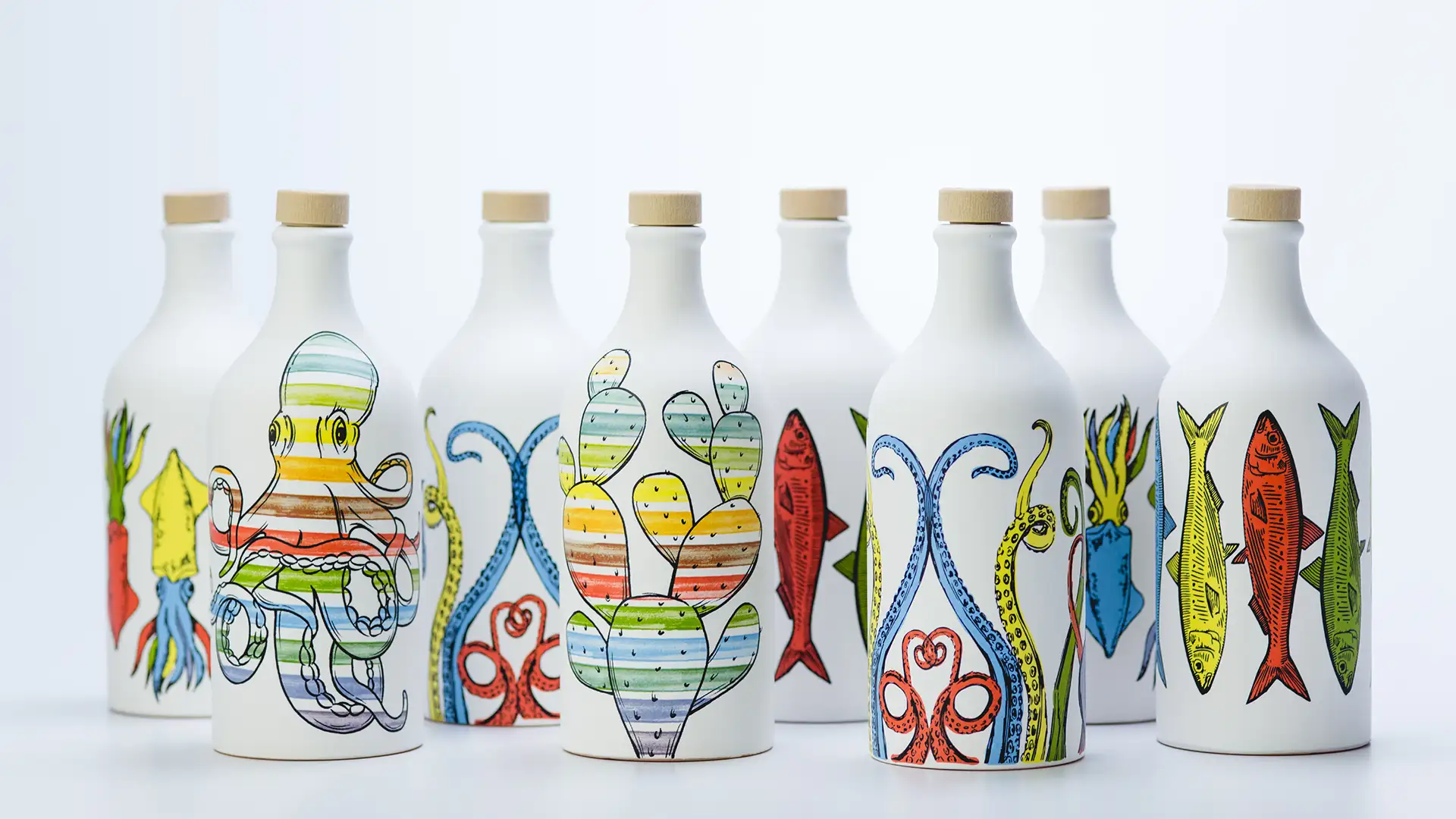 Vista d'insieme della gamma completa degli orci in ceramica Muraglia Orci di Mare, con le diverse decorazioni marine (polpo, fico d'india, calamari, pesci) in fila su sfondo chiaro