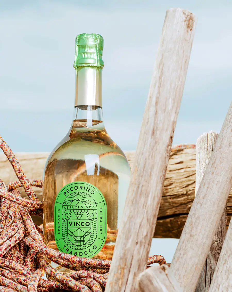 Bottiglia di Vinco Spumante Pecorino Trabocco immersa tra legni e corde di un trabocco abruzzese