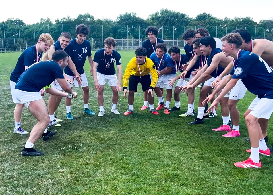 Gruppe von jungen Burschen in Fußballdressen mit Medaillen um den Hals in Vorbereitung auf einen gemeinsamen Jubelschrei.