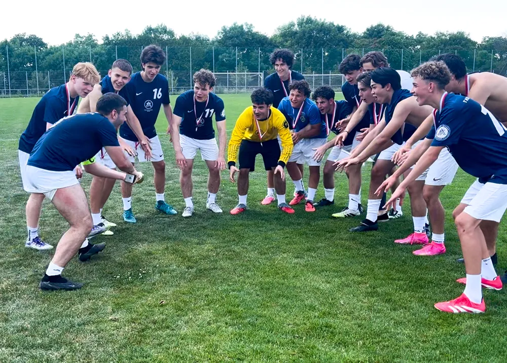 Gruppe von jungen Burschen in Fußballdressen mit Medaillen um den Hals in Vorbereitung auf einen gemeinsamen Jubelschrei.