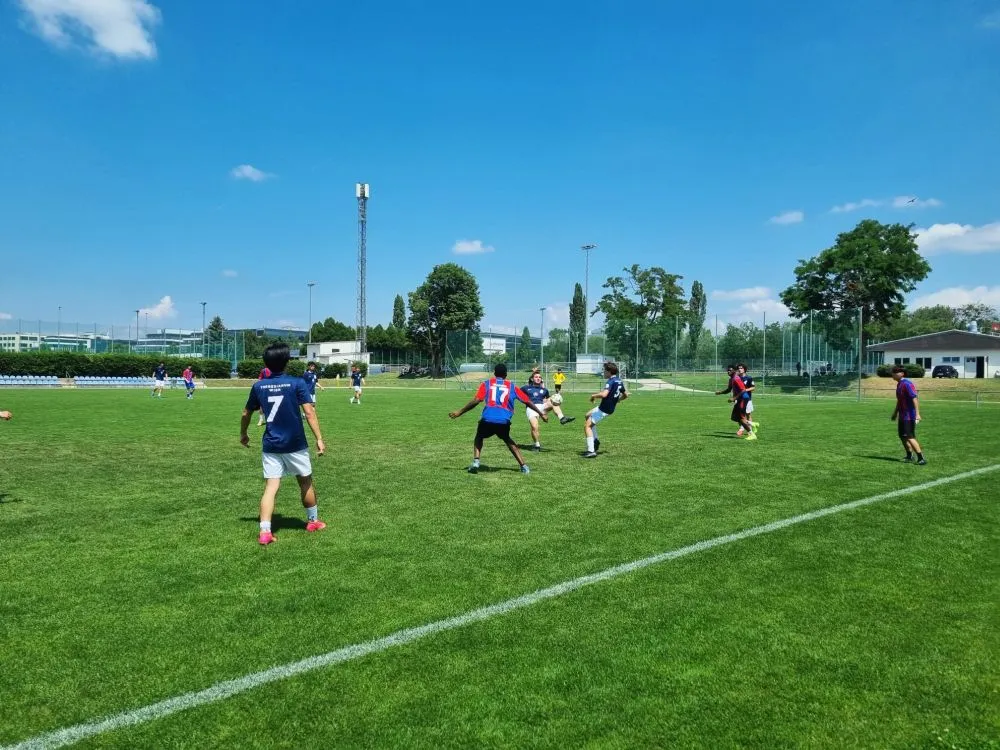 Männer in Fußballdressen am Fußballfeld kickend.
