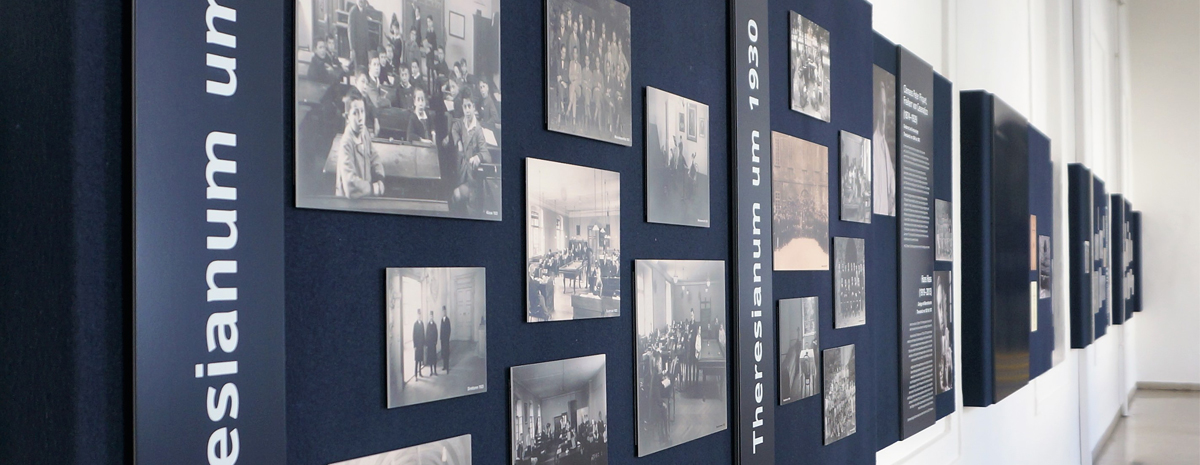 Aufnahme eines Ganges mit dunkelblauen Wandpaneelen mit alten Abbildungen