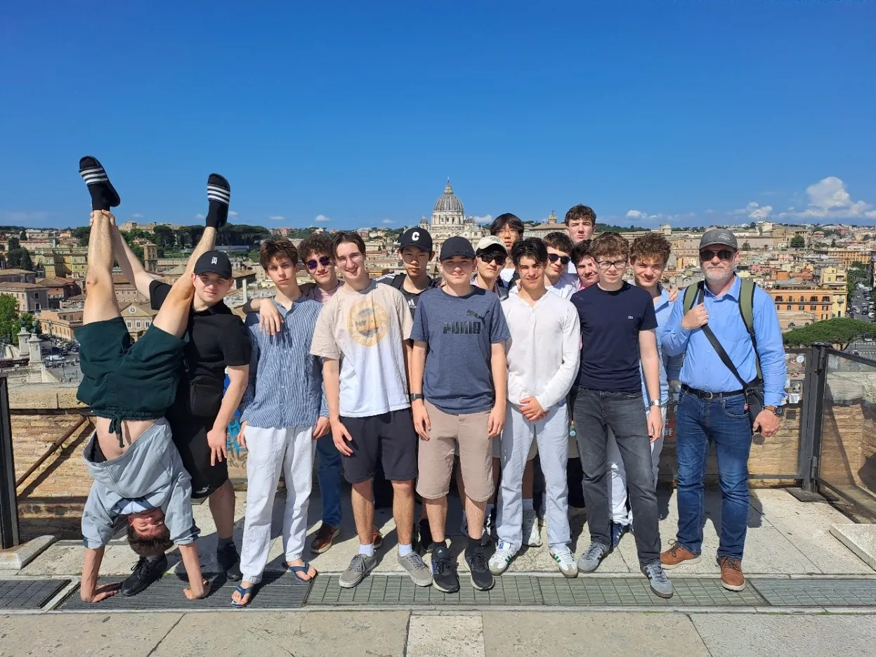 Gruppe von jungen Burschen unter strahlend blauem Himmel in sommerlichen Outfit vor der Kulisse Roms.