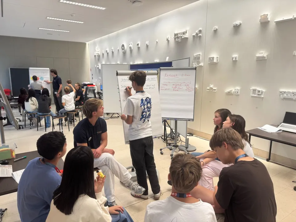 Schüler:innen in Workshop Setting an einer Flipchart arbeitend.