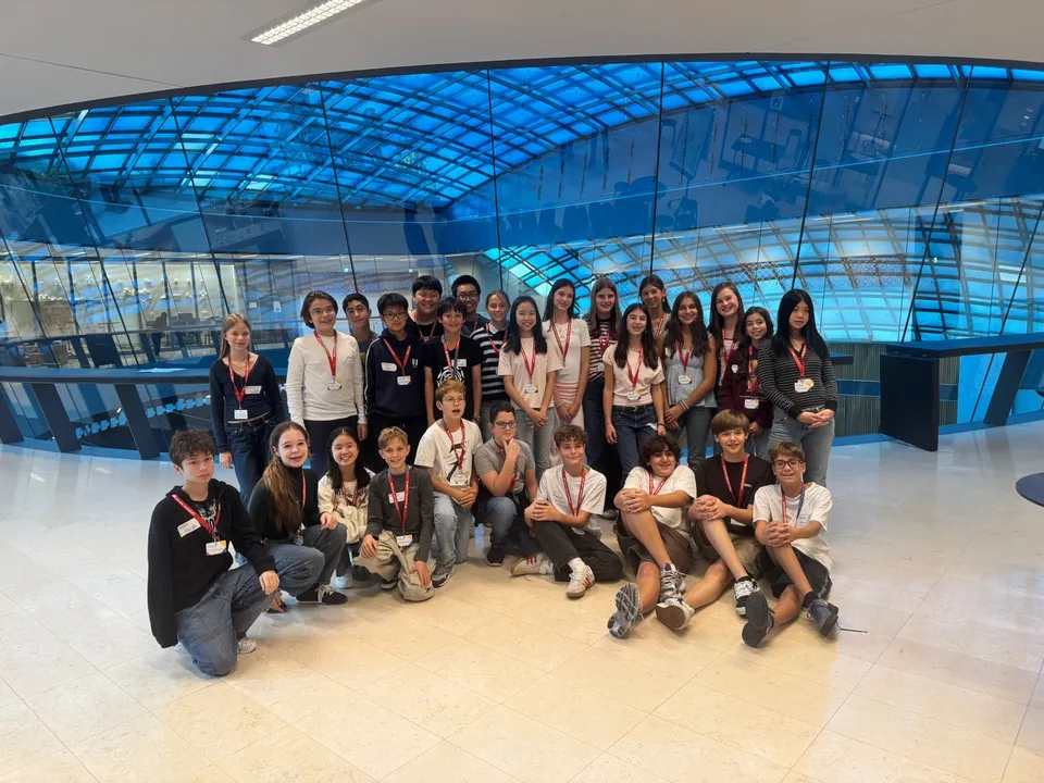 Gruppe von Schüler:innen vor einer Glaskuppel stehend und sitzend.