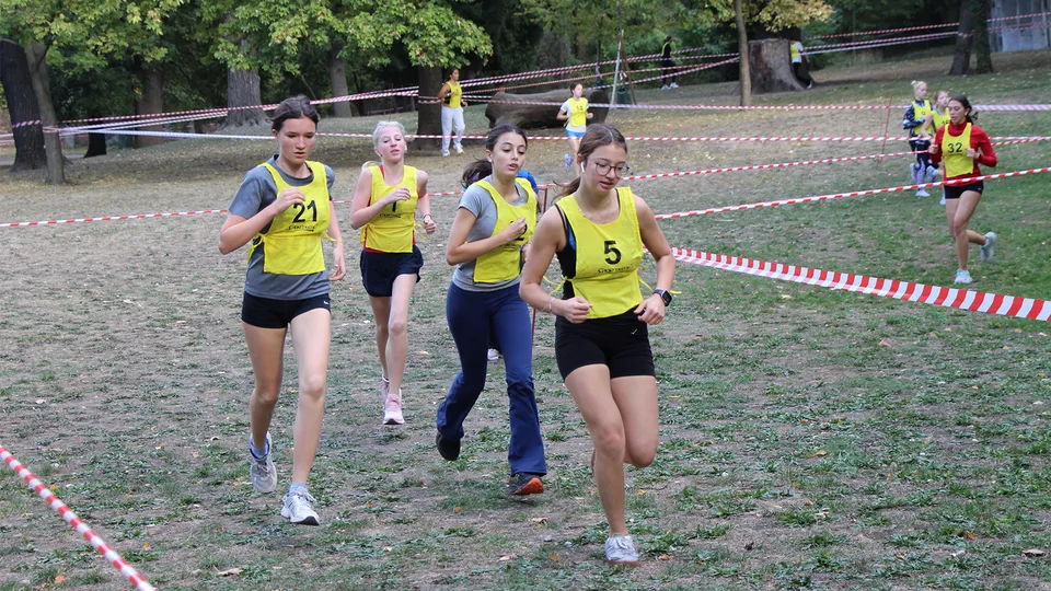 Junge Mädchen mit Startnummer auf einer Laufbahn und Querfeldein laufend.