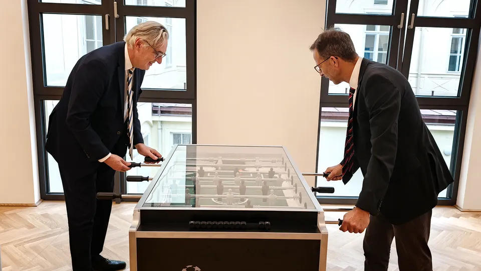 Zwei Männer mit Anzug an einem Tischfussballtisch.
