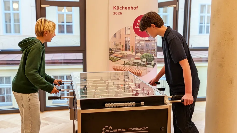 Zwei junge Burschen spielen Tischfußball.