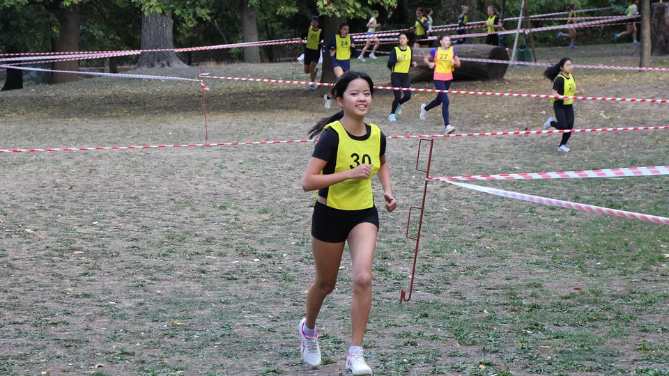 Junge Mädchen mit Startnummer auf einer Laufbahn und Querfeldein laufend.