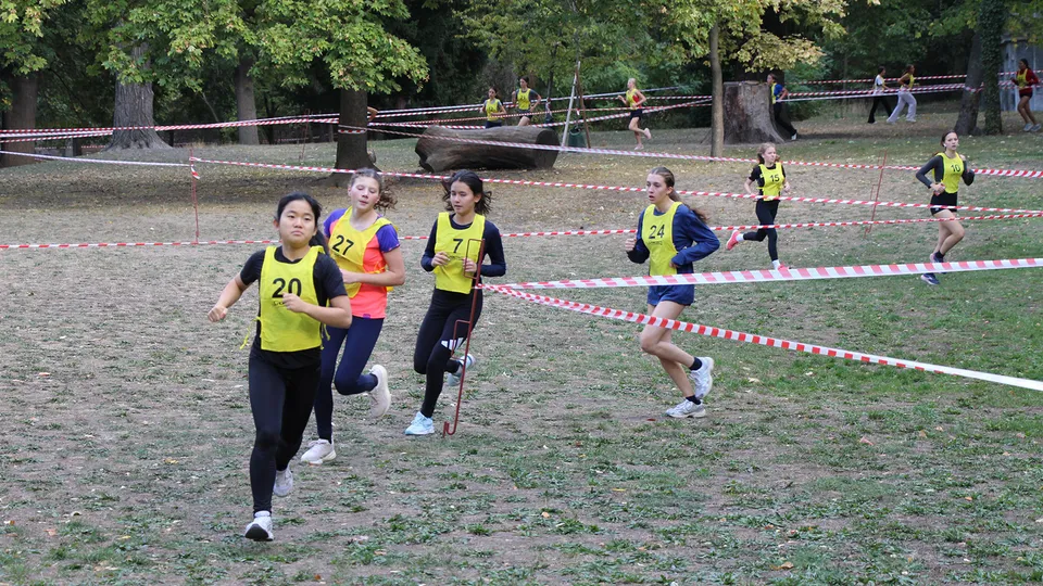 Junge Mädchen mit Startnummer auf einer Laufbahn und Querfeldein laufend.