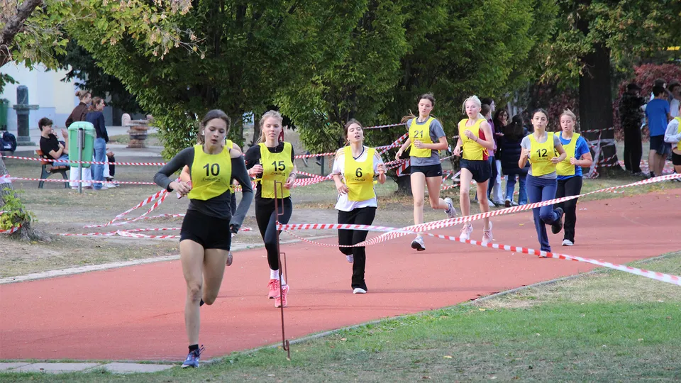 Junge Mädchen mit Startnummer auf einer Laufbahn und Querfeldein laufend.