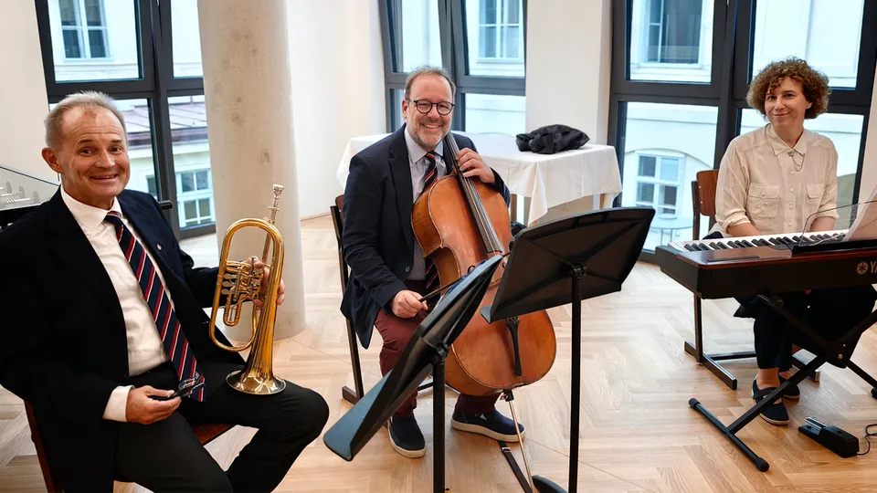 Musikalisches Trio bestehend aus zwei Männern und einer Frau mit Trompete, Cello und Klavier.