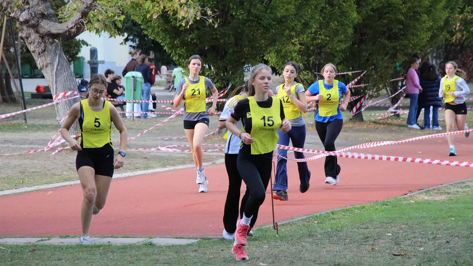 Junge Mädchen mit Startnummer auf einer Laufbahn und Querfeldein laufend.