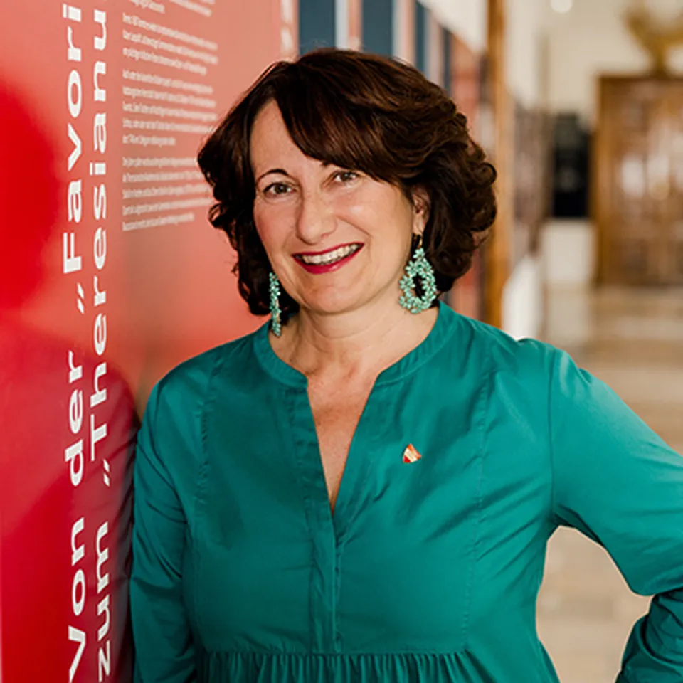 Portraitfoto einer Frau mit strahlendem Lachen, kurzen braunen Haaren und einer blauen Bluse