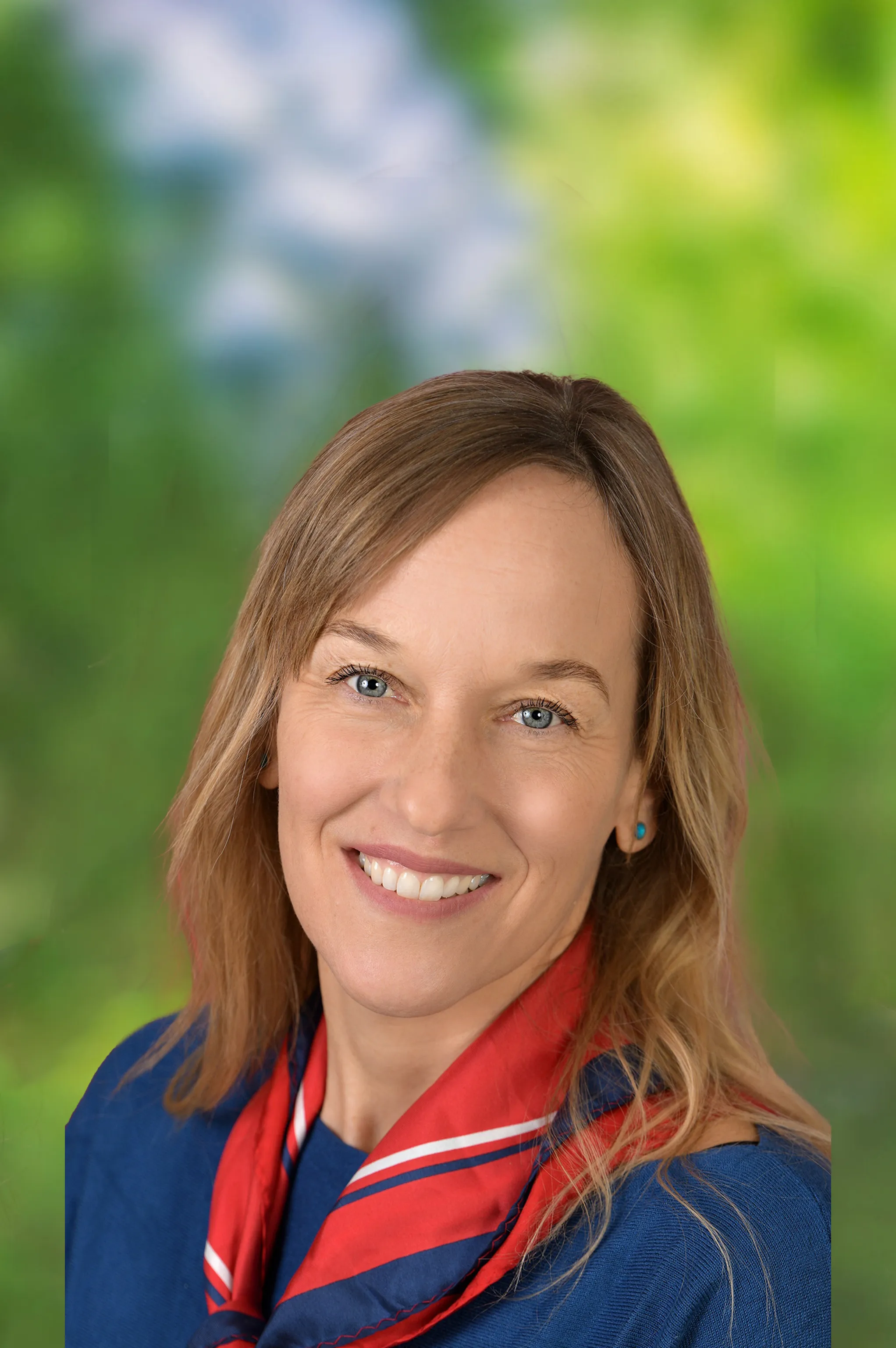 Portrait einer Frau freundlich lachend mit blonden Haaren und rotem Halstuch