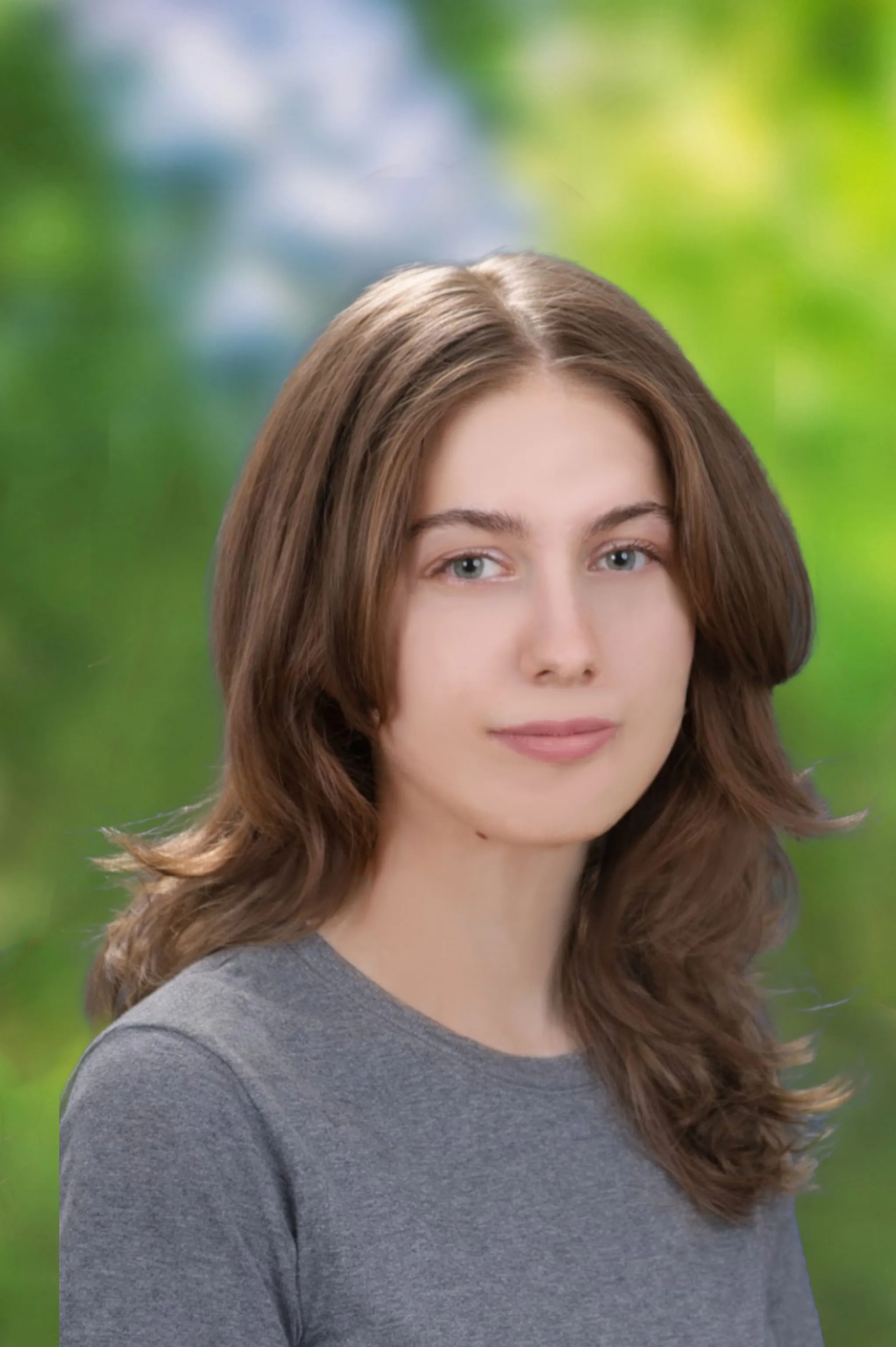 Portraitfoto einer jungen Frau mit brünetten langen Haaren und grauem Shirt vor grünem Hintergrund