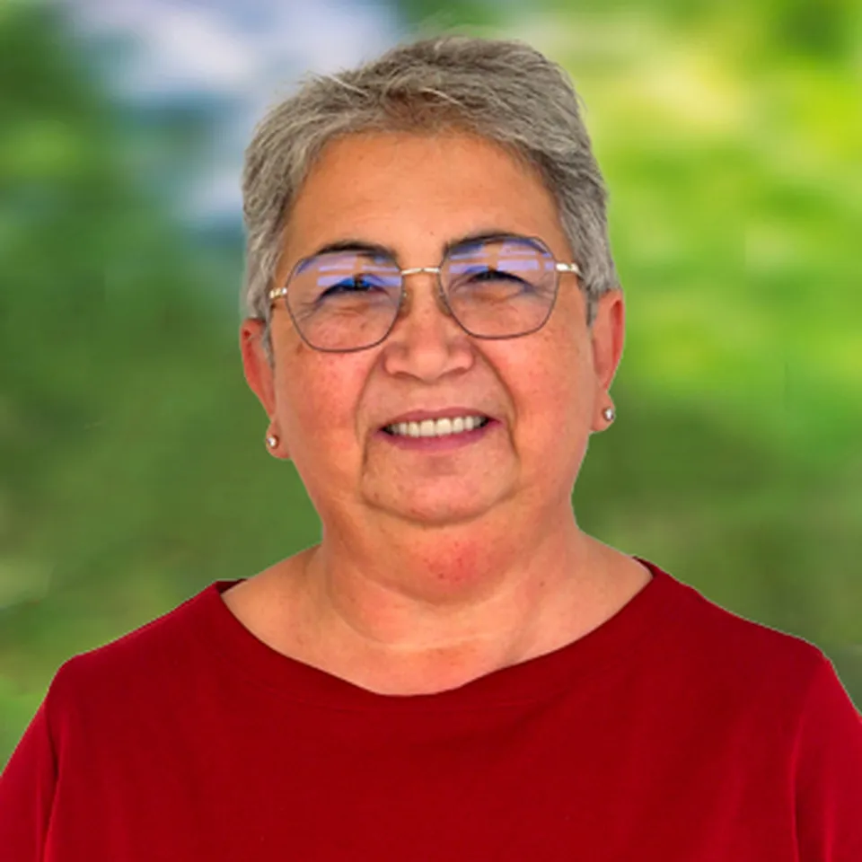 Freundlich lachende Dame mit kurzen grauen Haaren und Brille mit Ohrsteckern und rotem Pullover.