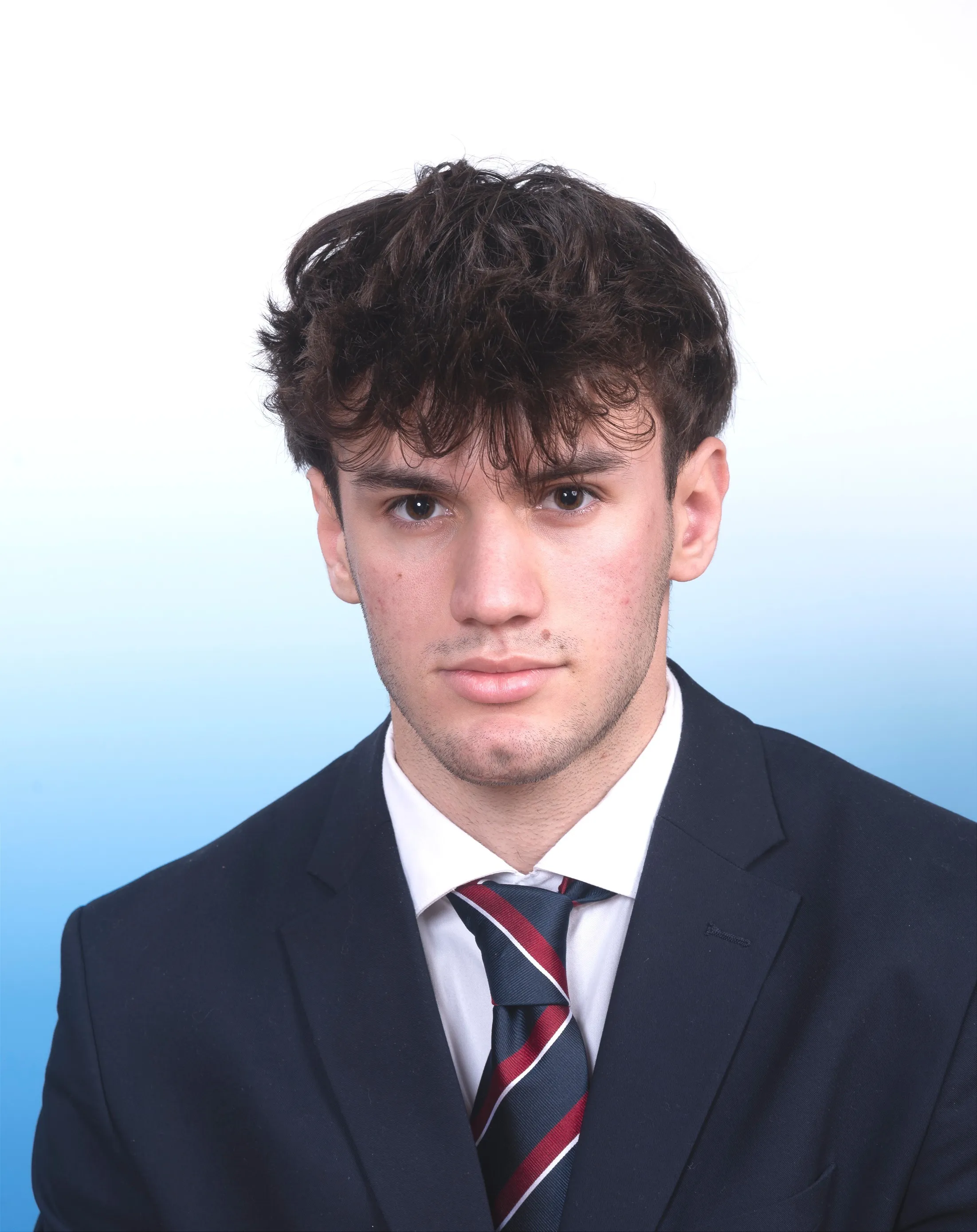 Junger Mann in Anzug und mit Krawatte und modern gestylten dunklen Haaren