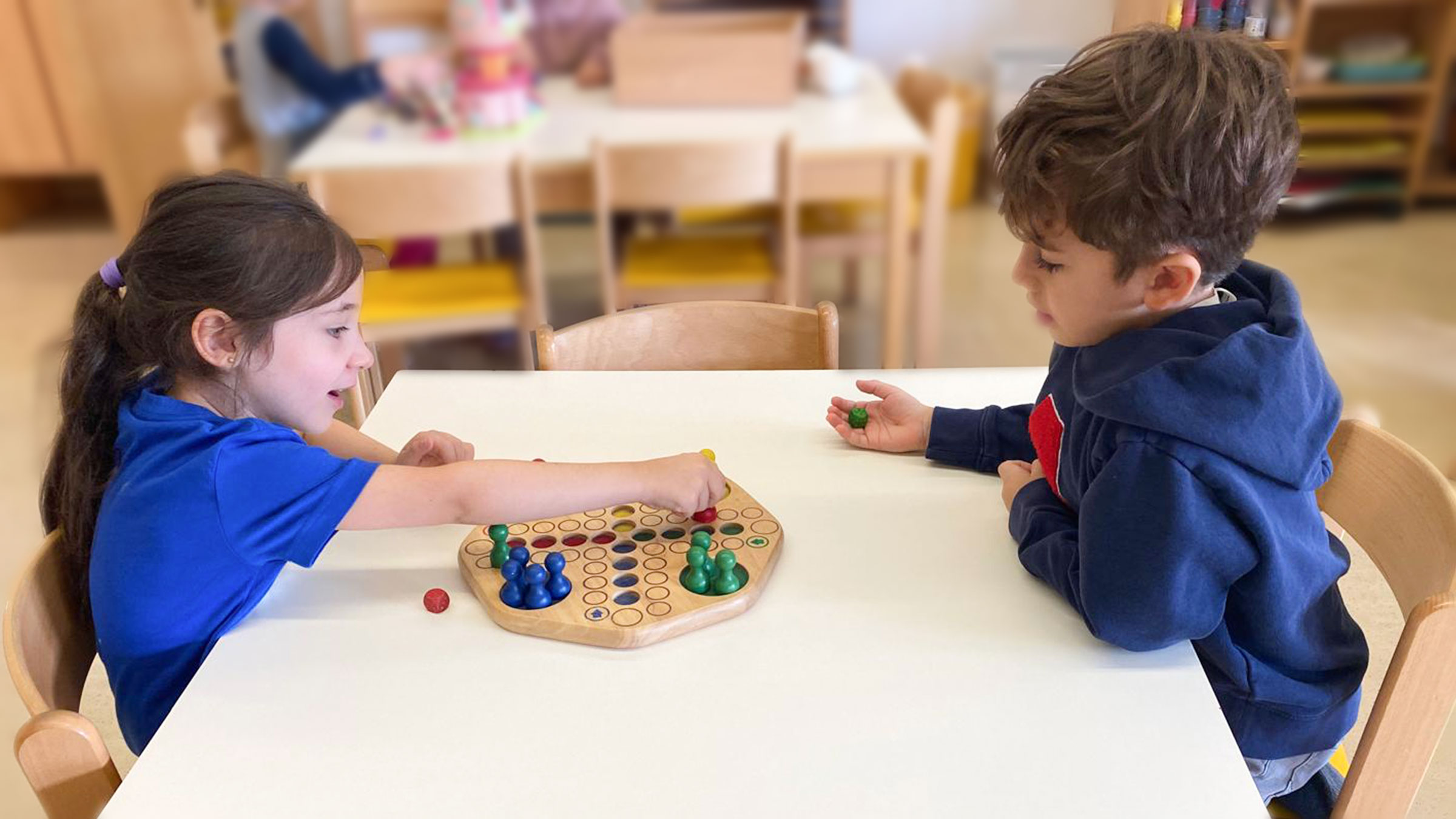 Zwei kleiner Kinder an einem Tisch sitzend, ein Brettspiel spielend