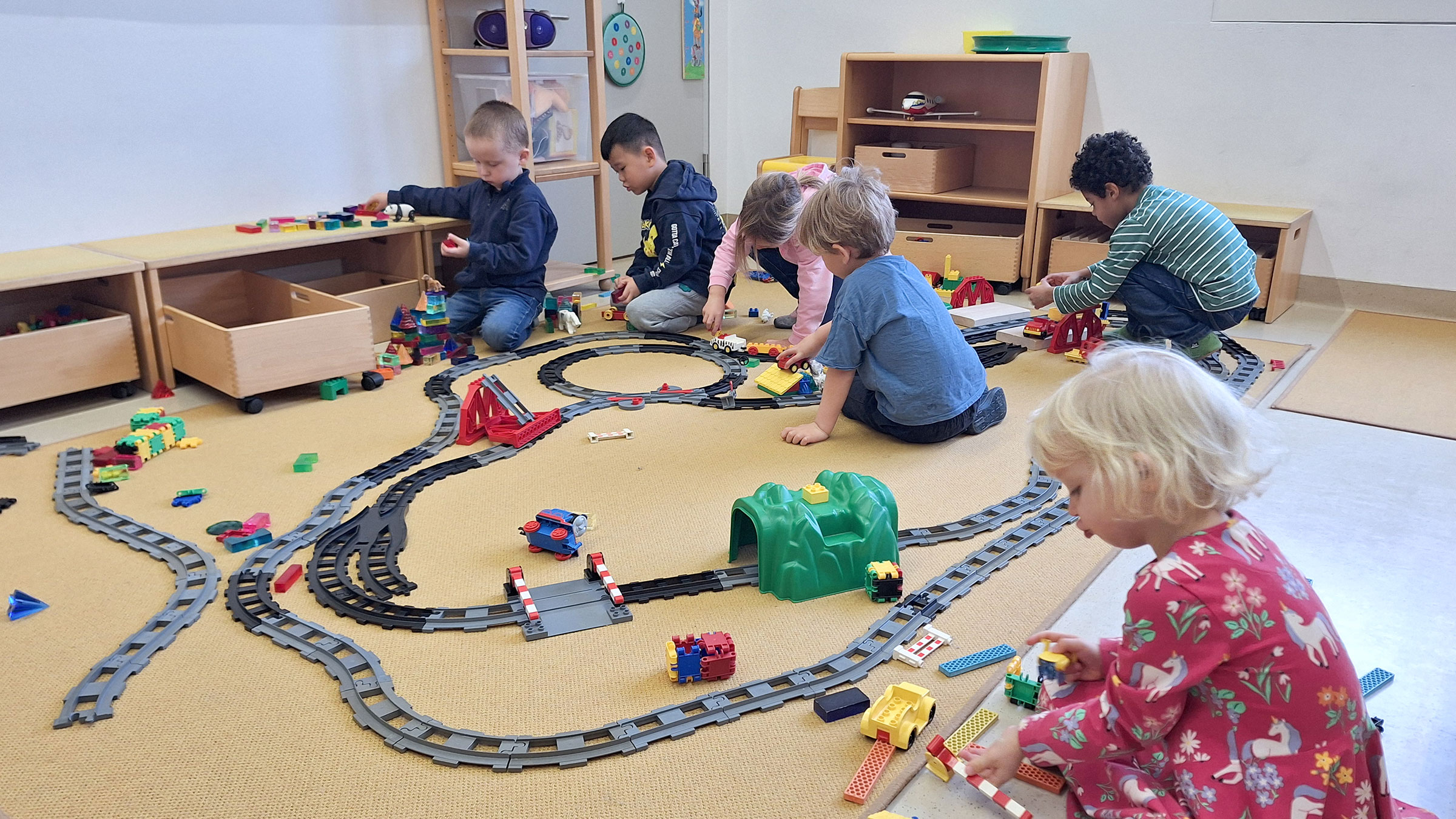 Gruppe von kleinen Kinder mit einer Modelleisenbahn am Boden spielend