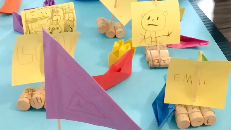 Kleine Flosse aus Kork mit gelben Papiersegeln und bunten Papierschiffchen.