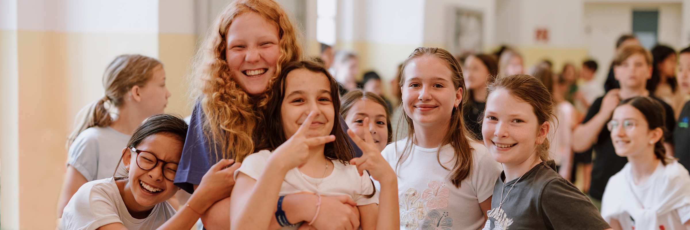 Gruppe von jungen Mädchen lachend und sich umarmend in einem Gang mit Kindern