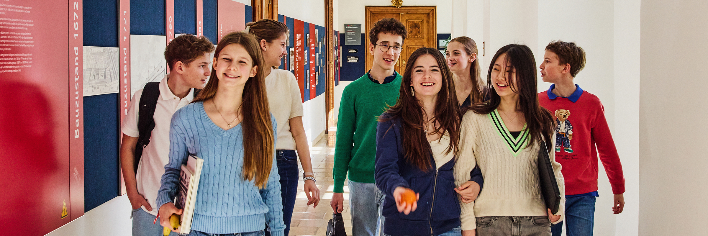 Gruppe von Teenagern in einem historischen Gang beschwingt entlang gehend.