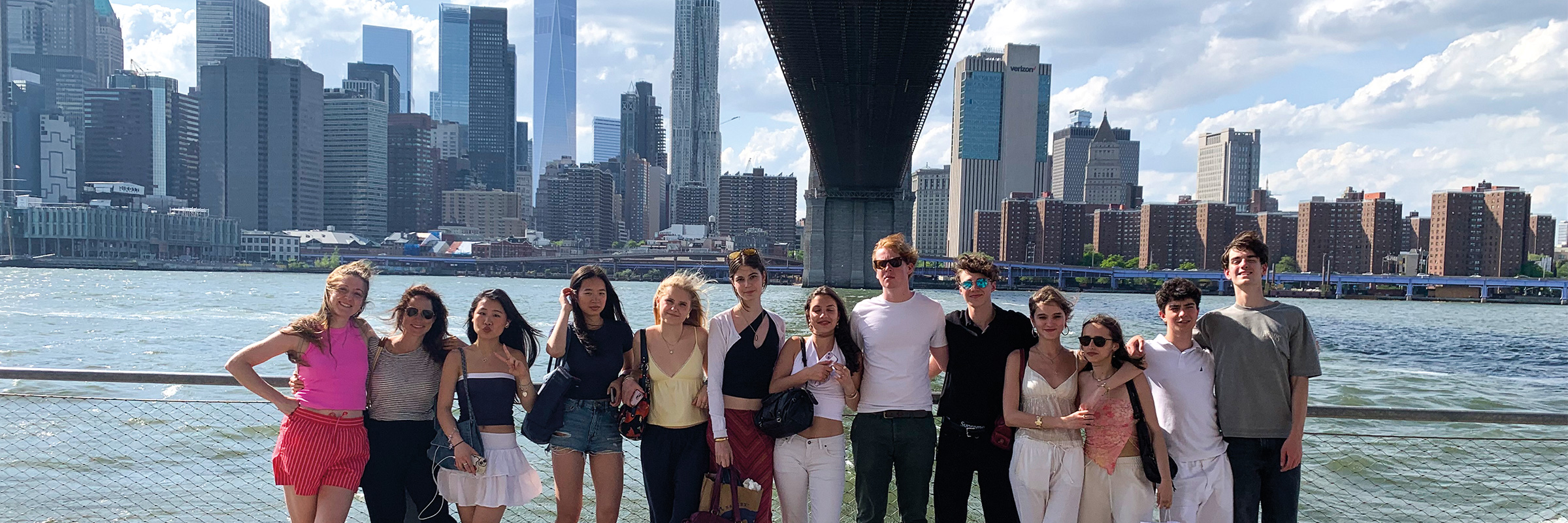 Gruppe von jungen Menschen an einem sonnigen Tag vor der Kulisse Manhattan stehend