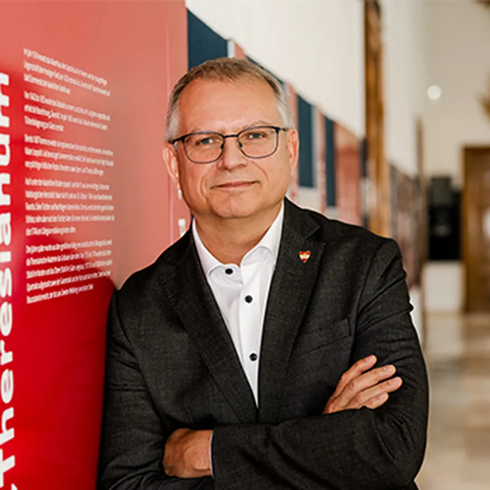 Ein Mann mit Brille, einem weißen Hemd und einer dunklen Jacke.