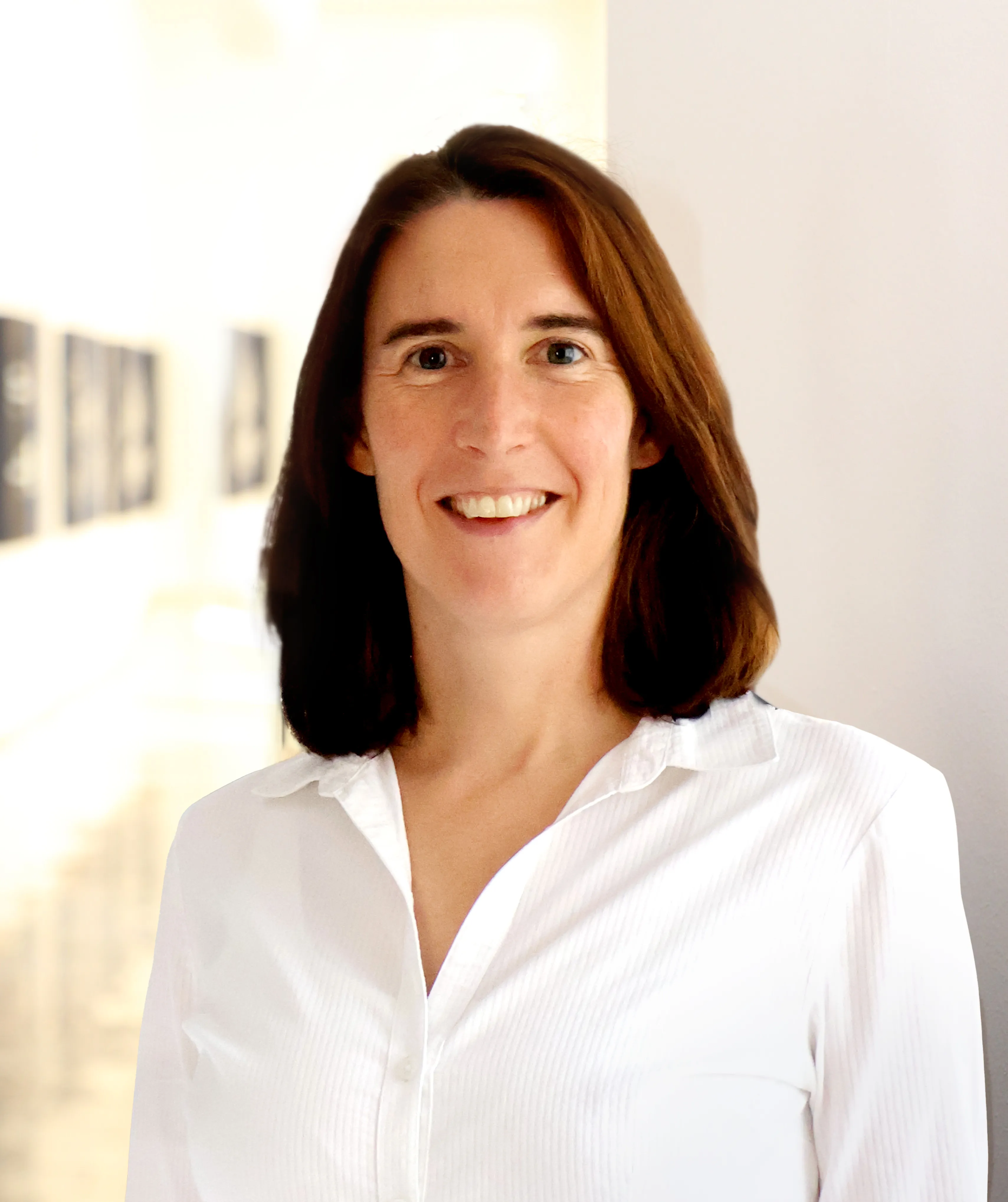 Lächelnde Frau mit kurzem braunen Haar und weißer Bluse.